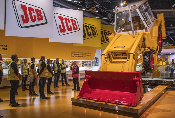 Eagle Plant employees looking around the JCB museum with large JCB logos and machine lifted up off the floor.
